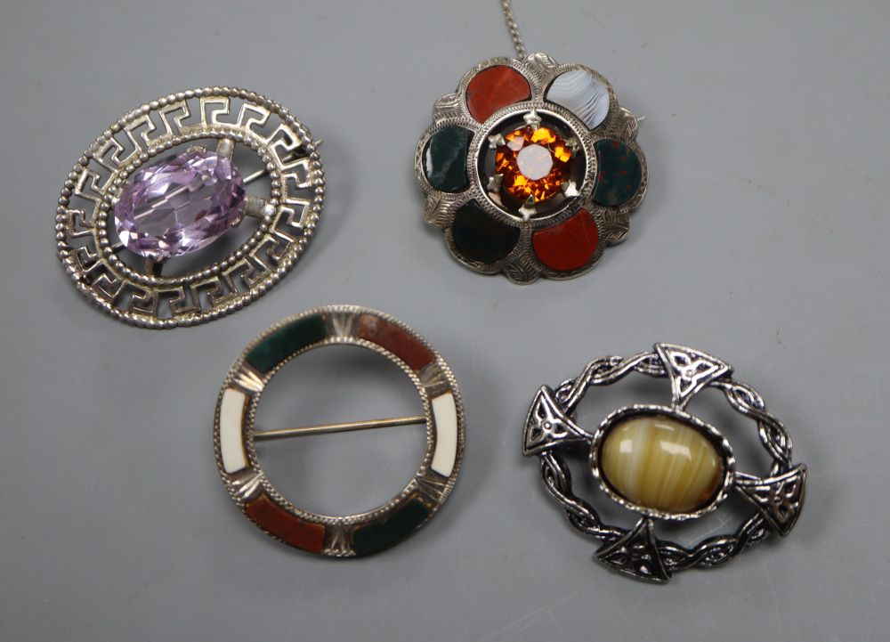 A Scottish pieced silver and amethyst set oval brooch, two white metal and Scottish hardstone brooches and one other brooch.